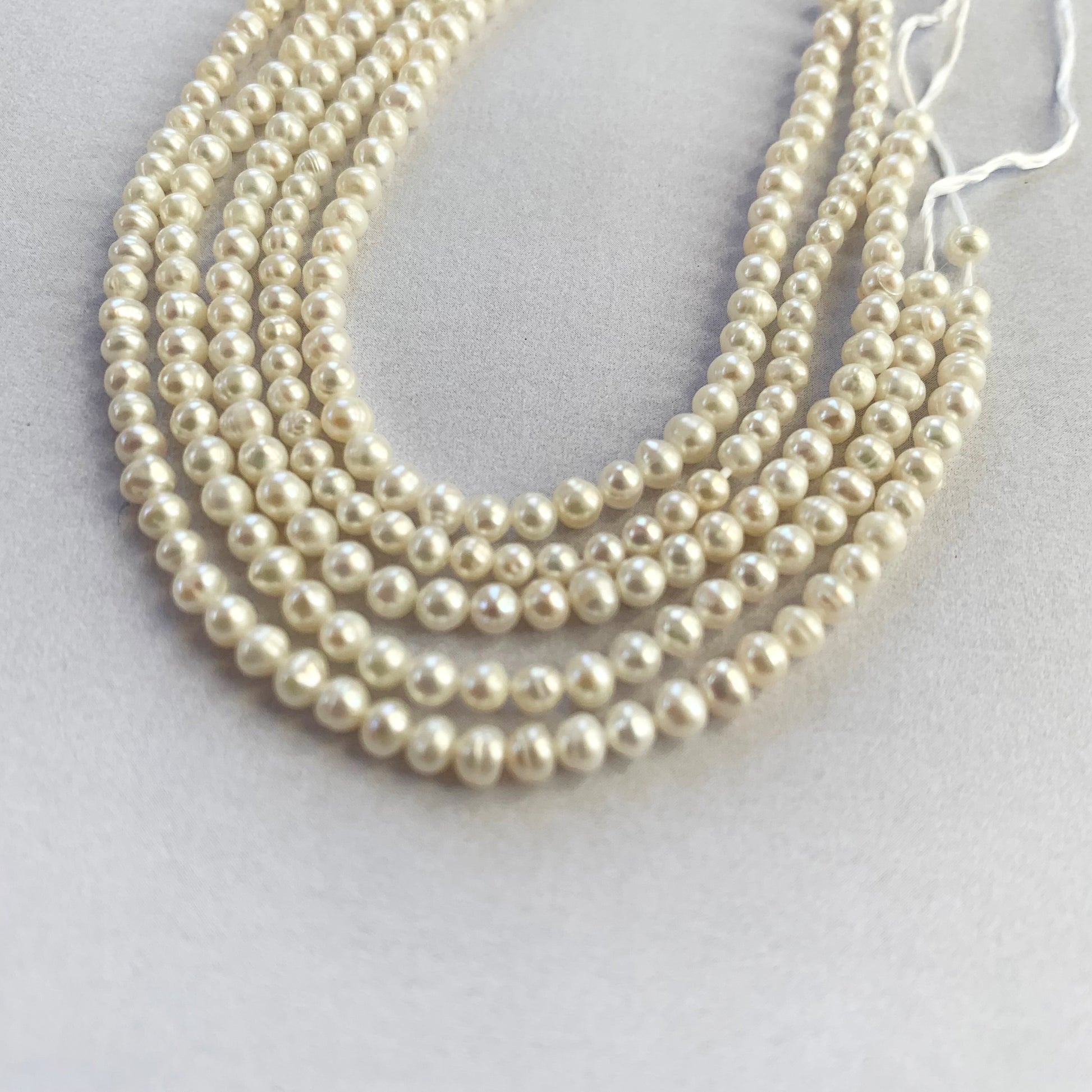 Neatly strung freshwater pearls in soft white tones, ideal for fine jewellery making.