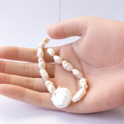 A person holds delicate pieces of freshwater pearls, showcasing their baroque design.