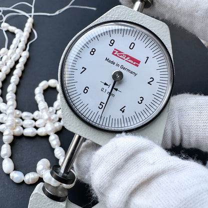 A dial gauge measures a baroque rice shaped Freshwater Pearl.