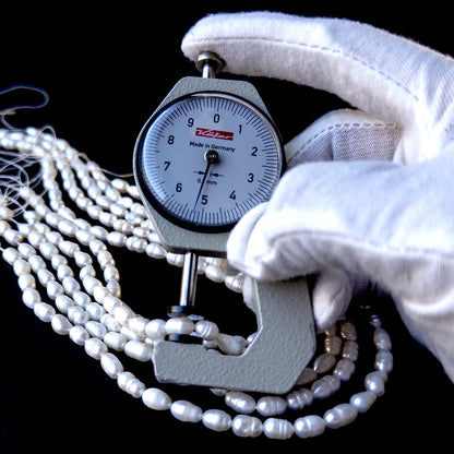 A dial gauge measures the freshwater baroque rice‑shaped 7.5–8.5mm x 5mm pearl.