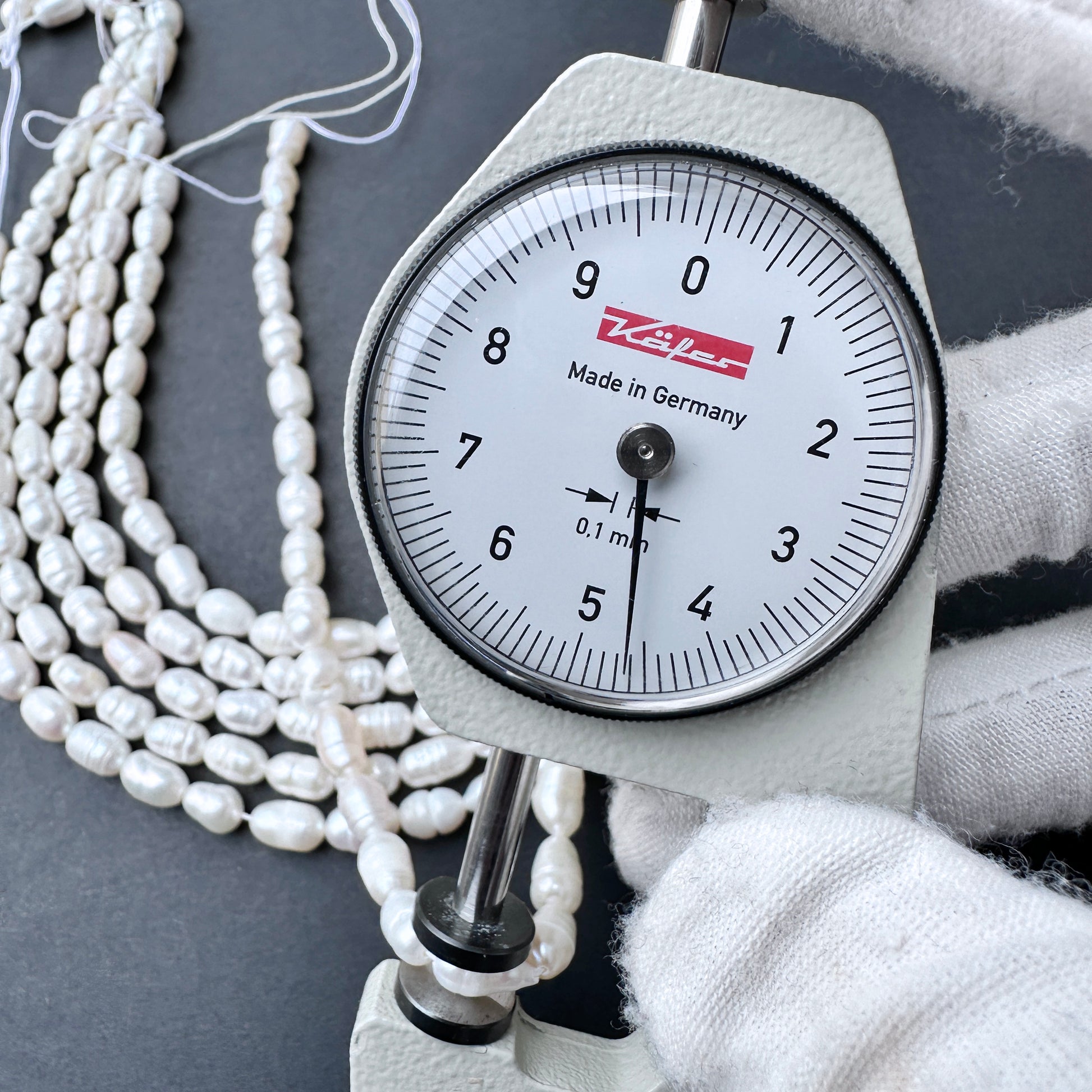 A dial gauge measures breadth of a baroque rice shaped Freshwater Pearl.