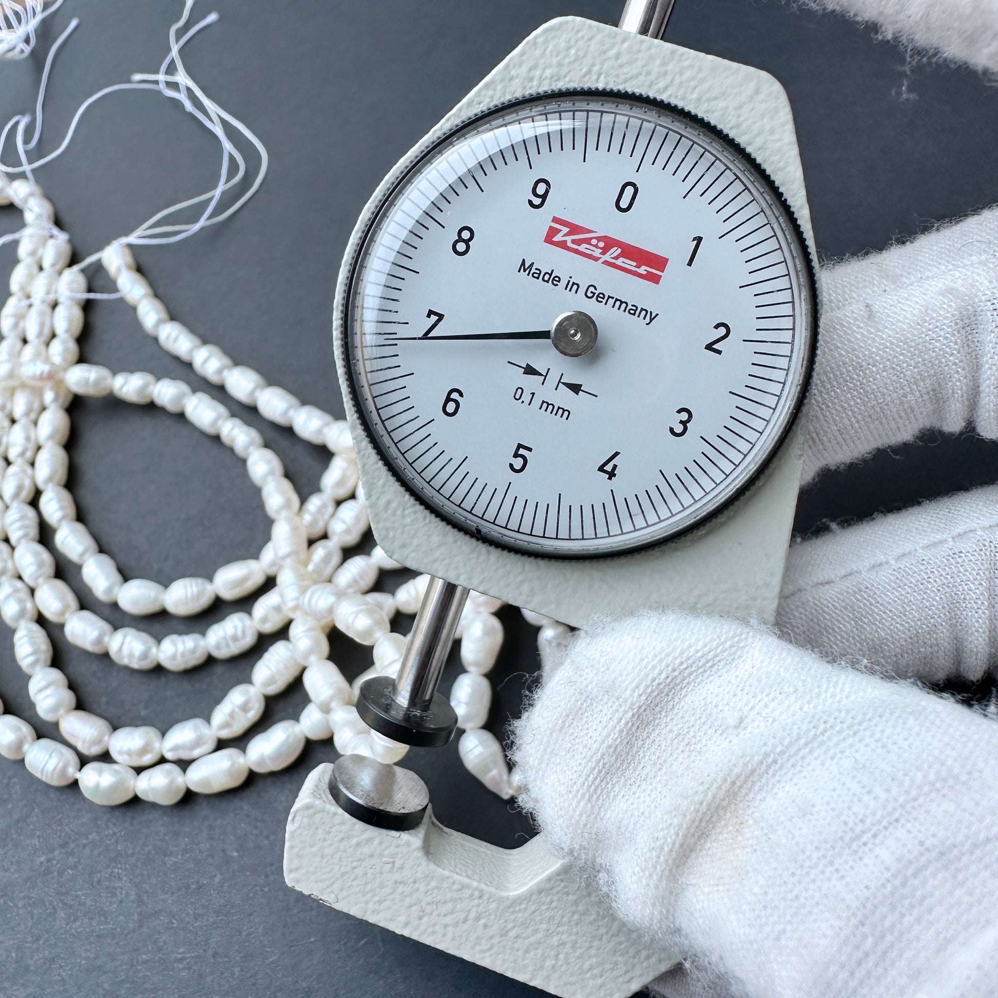 A dial gauge measures Length of a baroque rice shaped Freshwater Pearl.