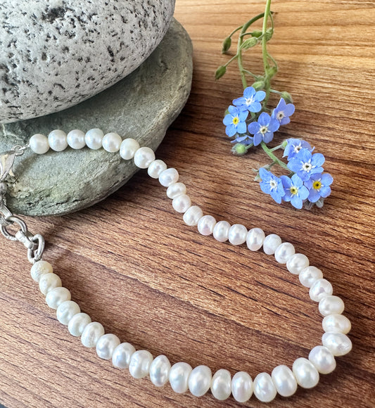 Close-up of freshwater pearl bracelet featuring smooth rondelle cut stone beads, soft white lustre and polished shine.