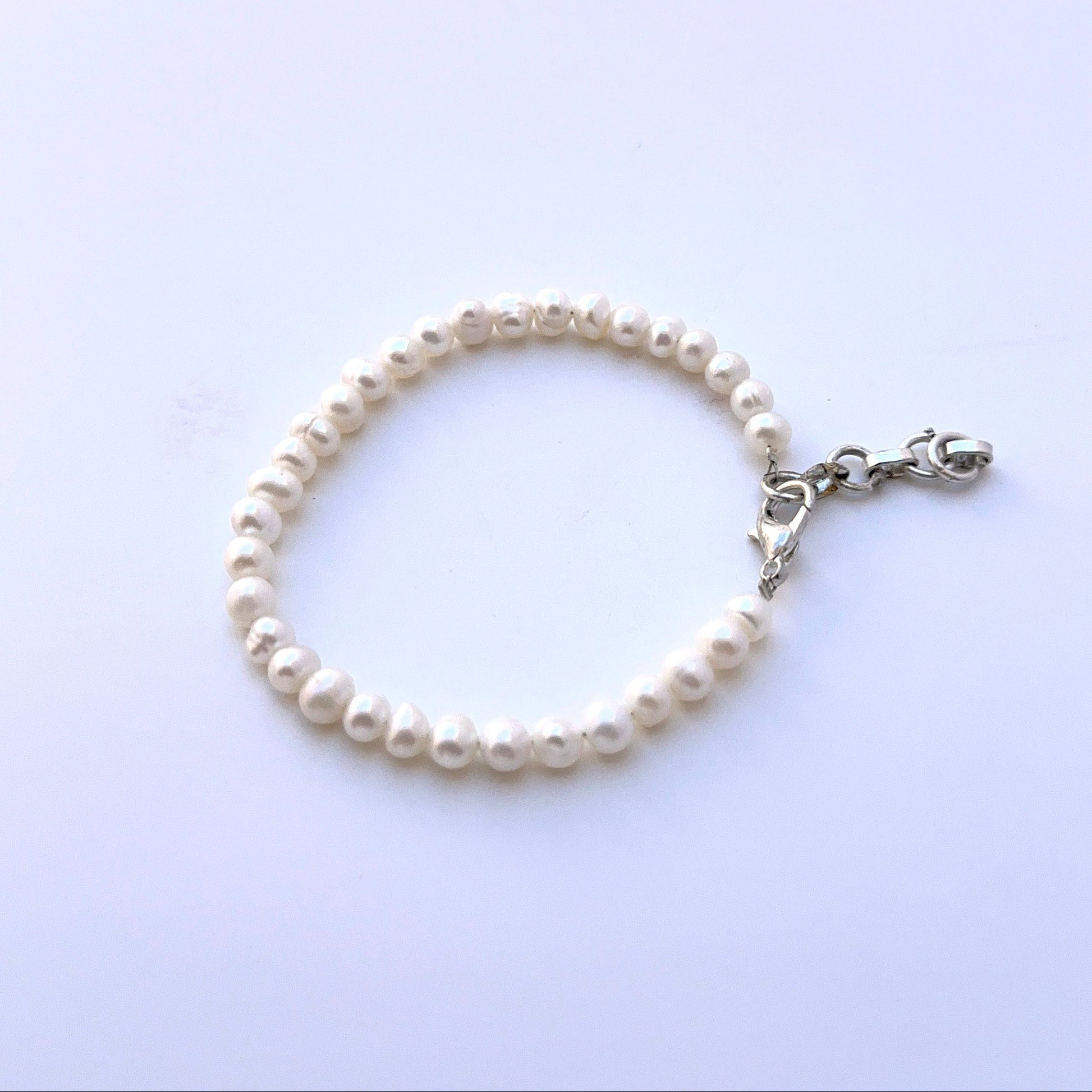 Close‑up of smooth rondelle freshwater pearls arranged on a polished bracelet.