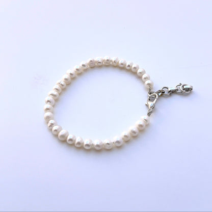 Close‑up of smooth rondelle freshwater pearls arranged on a polished bracelet.