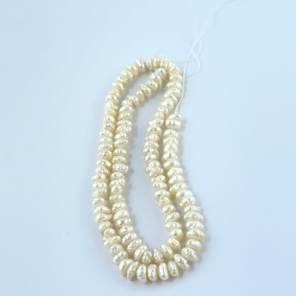 Close‑up of Freshwater Pearl stone beads arranged in a strand with textured surfaces.