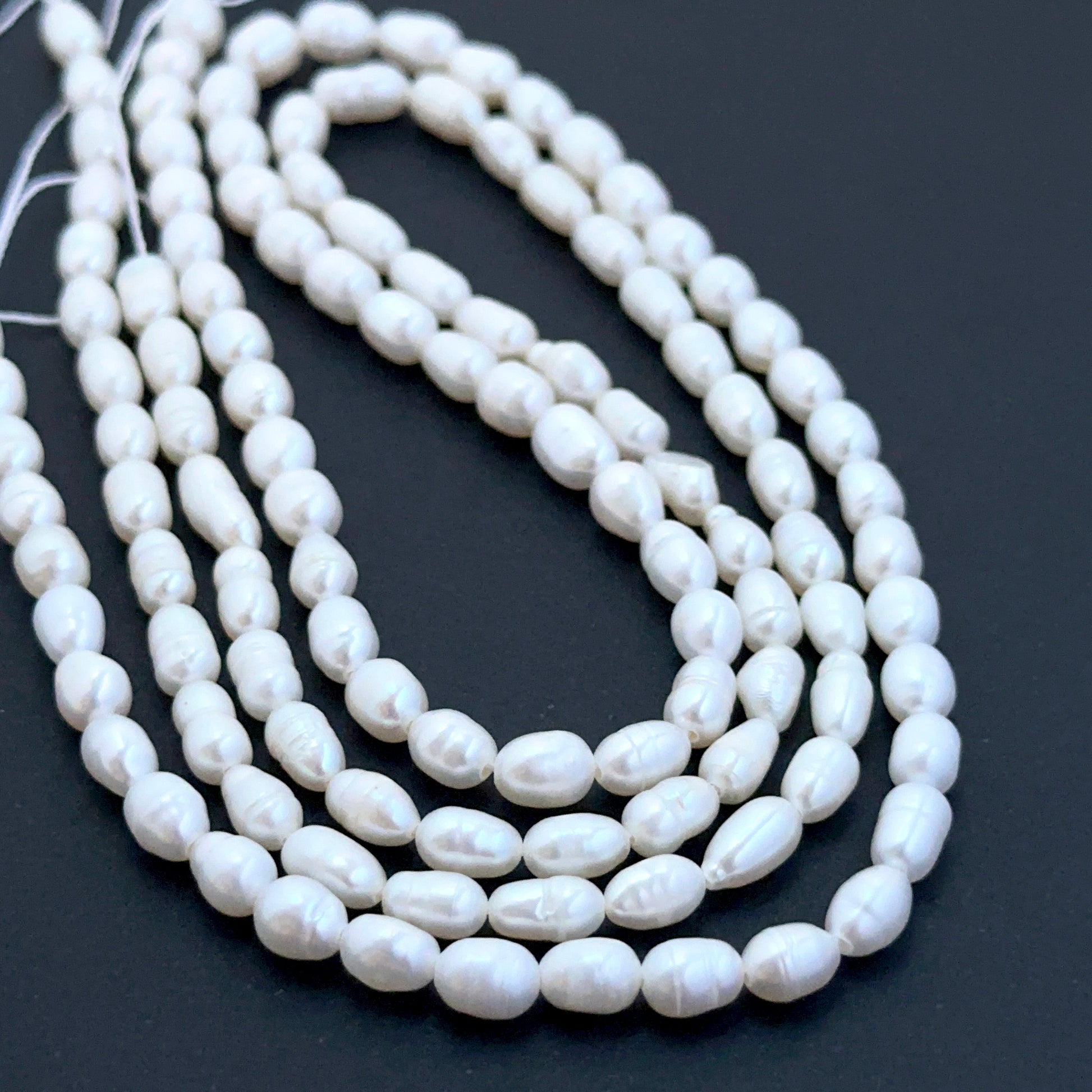 Close‑up of 4mm and 4.2–2.5mm freshwater pearl beads showing smooth surfaces ideal for natural gemstone beads for DIY jewellery.