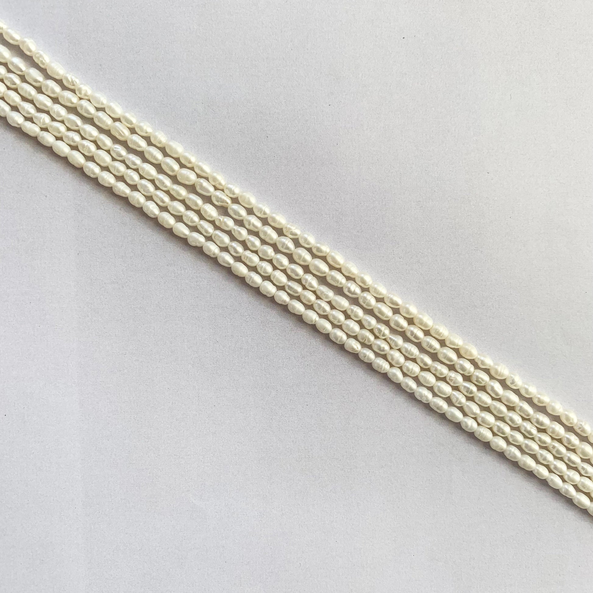 Glossy rice-shaped freshwater pearls radiating soft white hues on a delicate string.