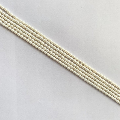 Glossy rice-shaped freshwater pearls radiating soft white hues on a delicate string.