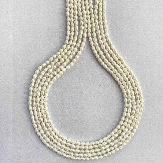 Close-up of white freshwater pearls in rice shape, arranged in a neat 40cm strand.