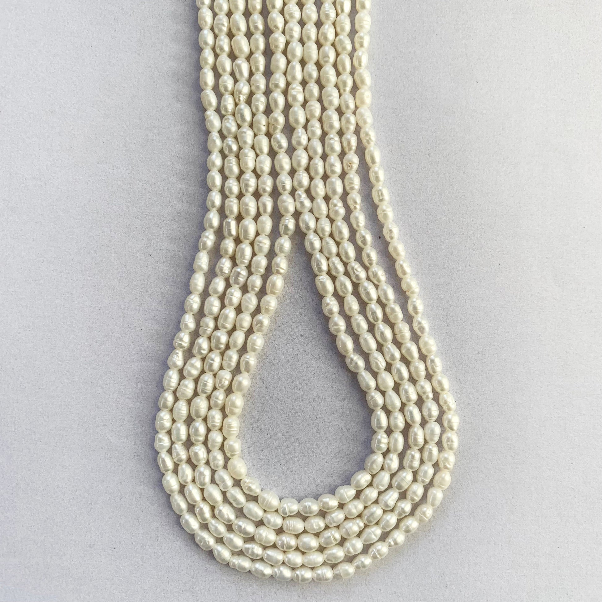 Smooth oval freshwater pearls with 3.0-3.3mm sizing displayed in uniform rows.
