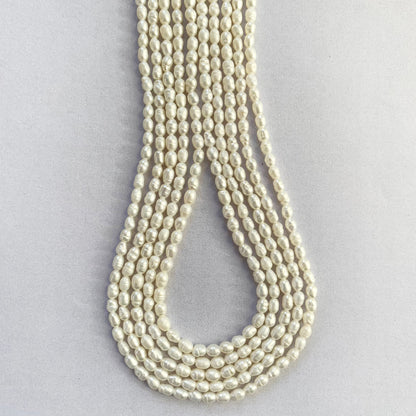 Smooth oval freshwater pearls with 3.0-3.3mm sizing displayed in uniform rows.