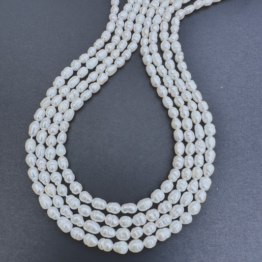 Close-up of Freshwater Pearl rice shaped beads with creamy-white tones and polished finish.