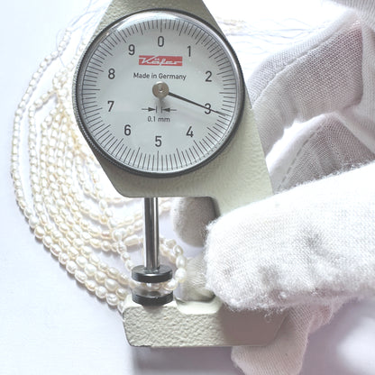 A dial gauge measures the Freshwater Pearl rice cut 3mm gemstone.