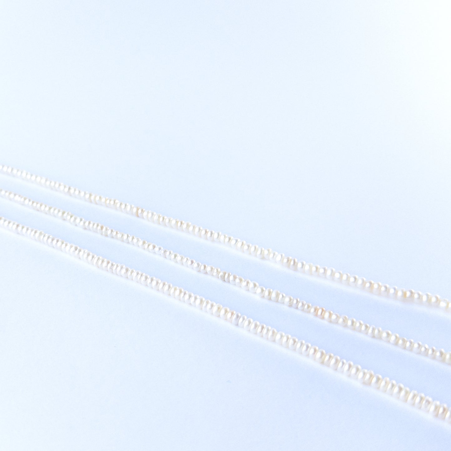 Natural Freshwater Pearl beads arranged in a strand, highlighting their rondelle cut and soft shimmering tones.