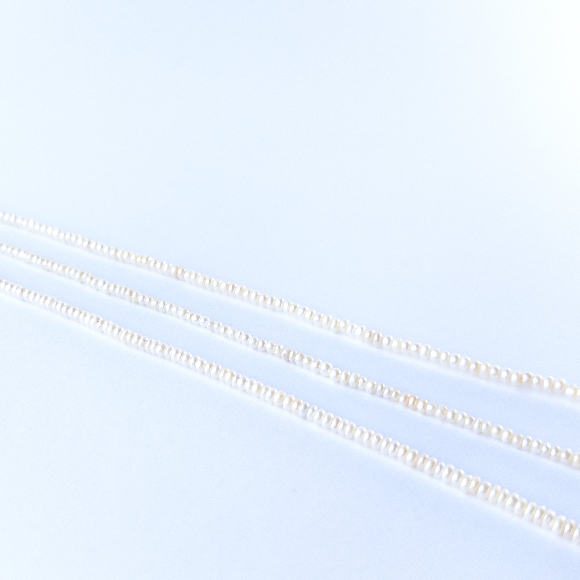 Natural Freshwater Pearl beads arranged in a strand, highlighting their rondelle cut and soft shimmering tones.