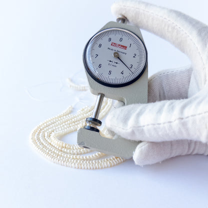 A dial gauge measures the Freshwater Pearls rondelle 3.1–3.5mm gemstone.
