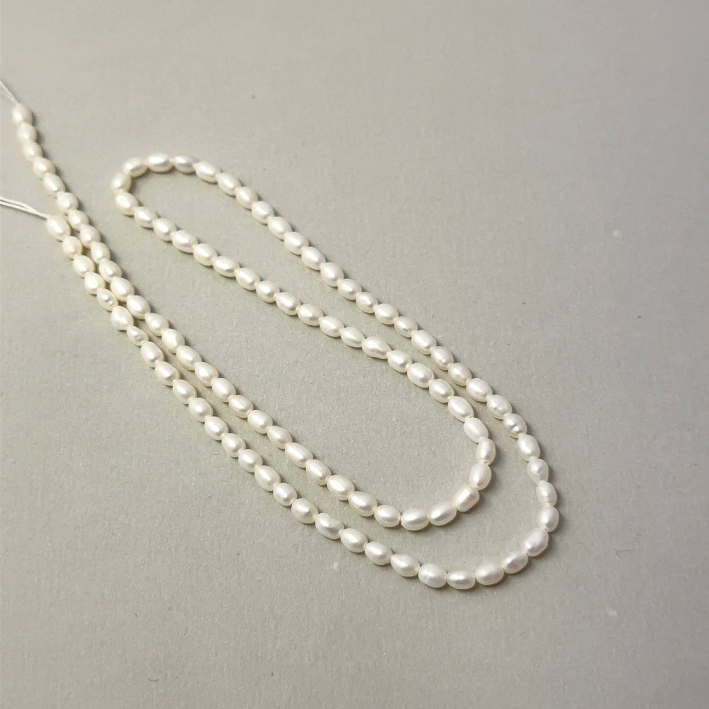 Close view of polished Freshwater Pearl smooth rice beads arranged on a 37cm strand for handmade jewellery components.