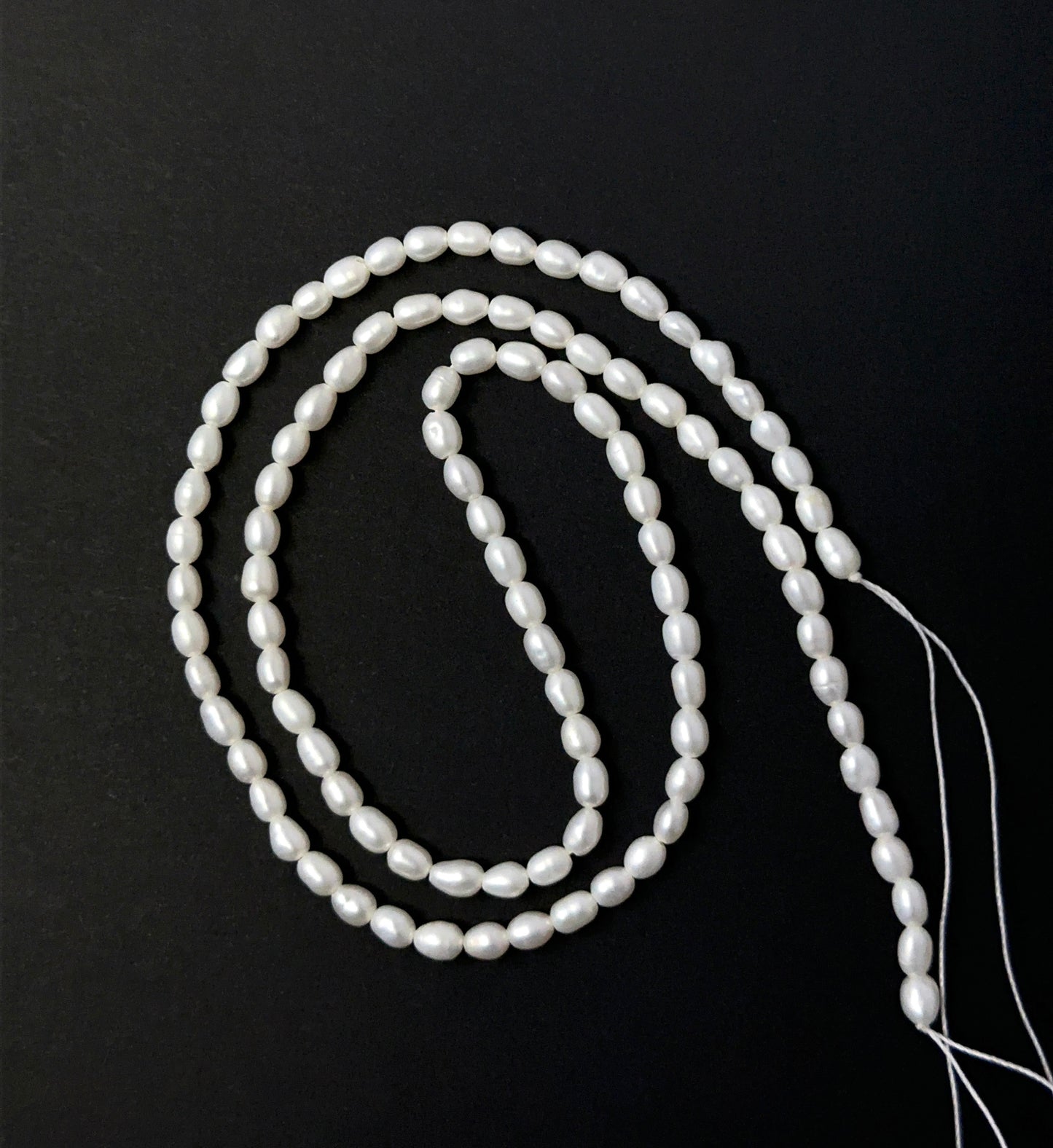 Freshwater Pearl smooth rice beads aligned on a strand, highlighting their glow, shape and quality stone beads.