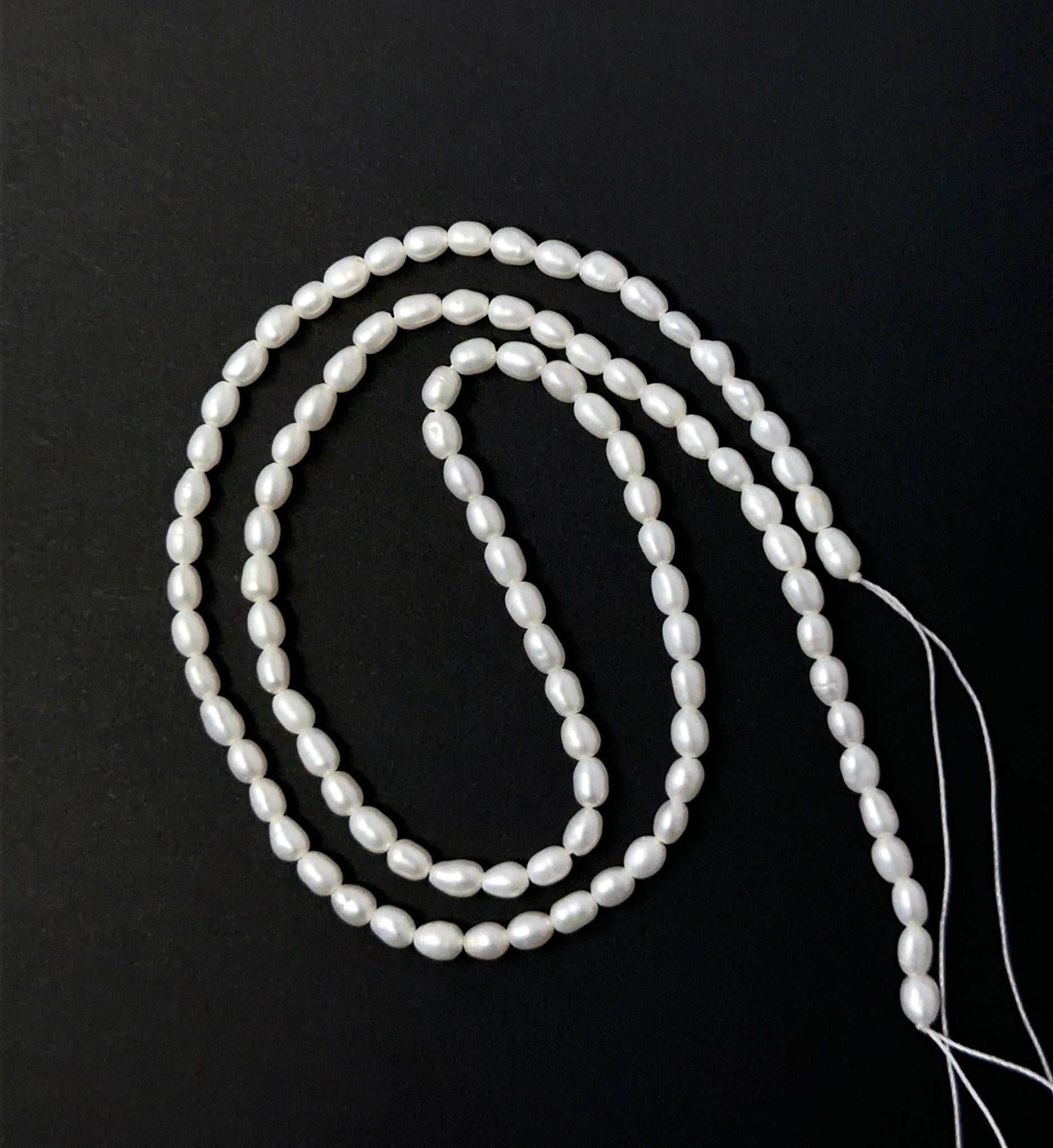 Freshwater Pearl smooth rice beads aligned on a strand, highlighting their glow, shape and quality stone beads.