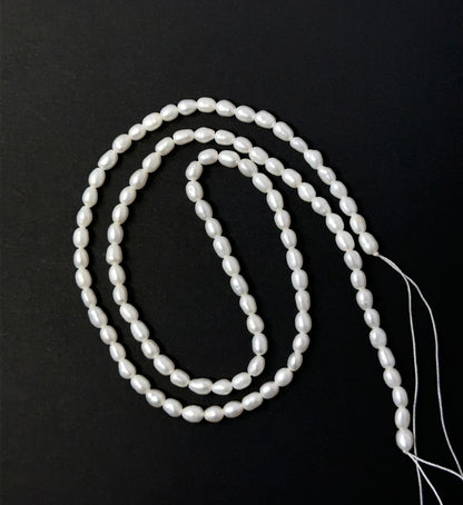 Freshwater Pearl smooth rice beads aligned on a strand, highlighting their glow, shape and quality stone beads.