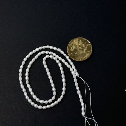 A coin is place near delicate strands of Freshwater Pearl beads for scale.