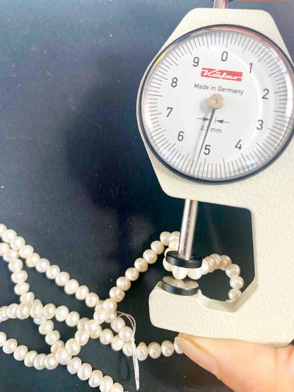 A dial gauge measures the Freshwater Pearl smooth rondelle 4.5–5mm gemstone.