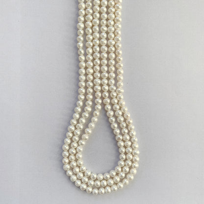 Soft white freshwater pearls with smooth round cut, 4.5-5.0mm sizes arranged on a strand.