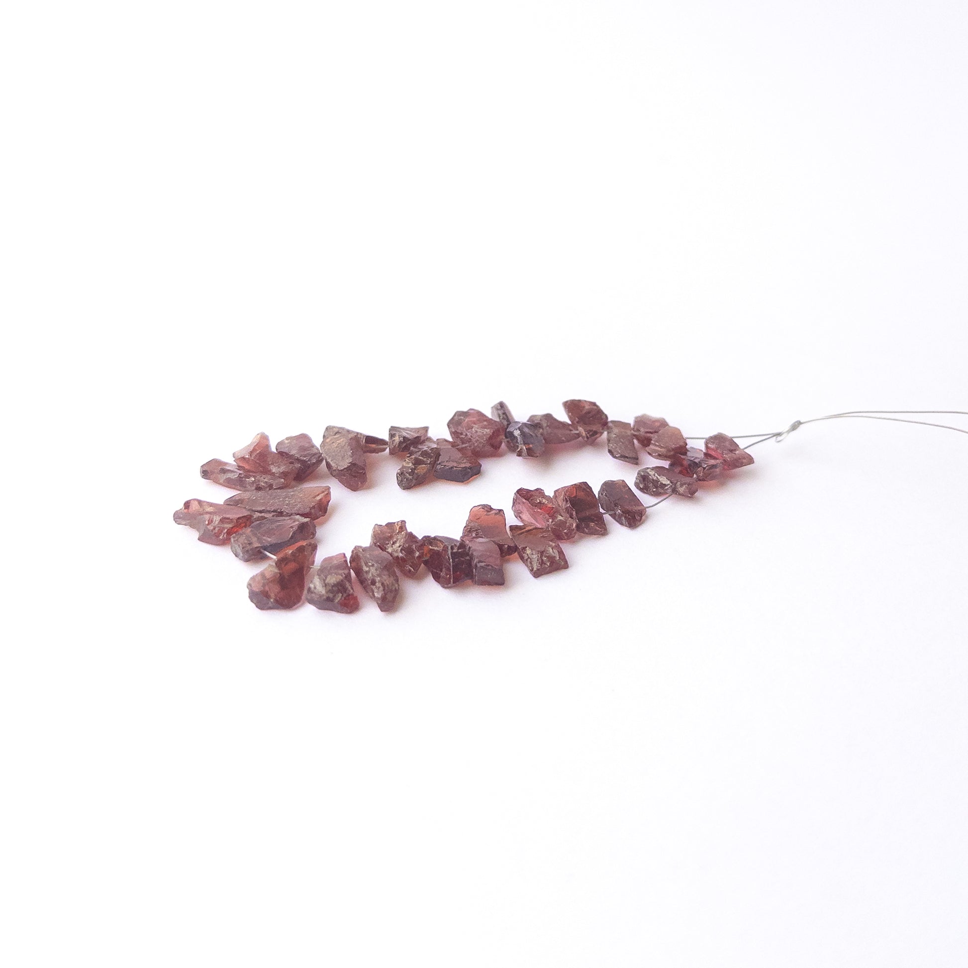 Authentic Garnet rough stone beads arranged to highlight their earthy tone and organic crystal form.