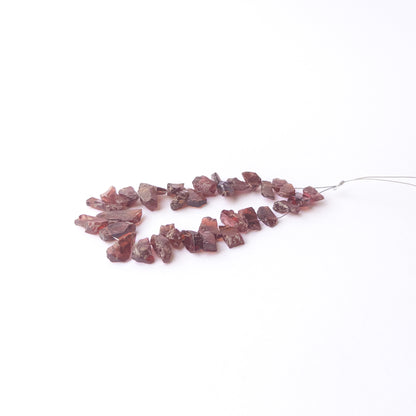 Authentic Garnet rough stone beads arranged to highlight their earthy tone and organic crystal form.