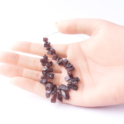 A person holds delicate strands of Garnet beads, showcasing their drilled rough design.