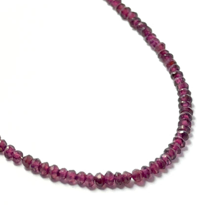 Garnet faceted rondelle beads with a glossy finish, arranged neatly on a strand for gemstone bead jewellery projects.