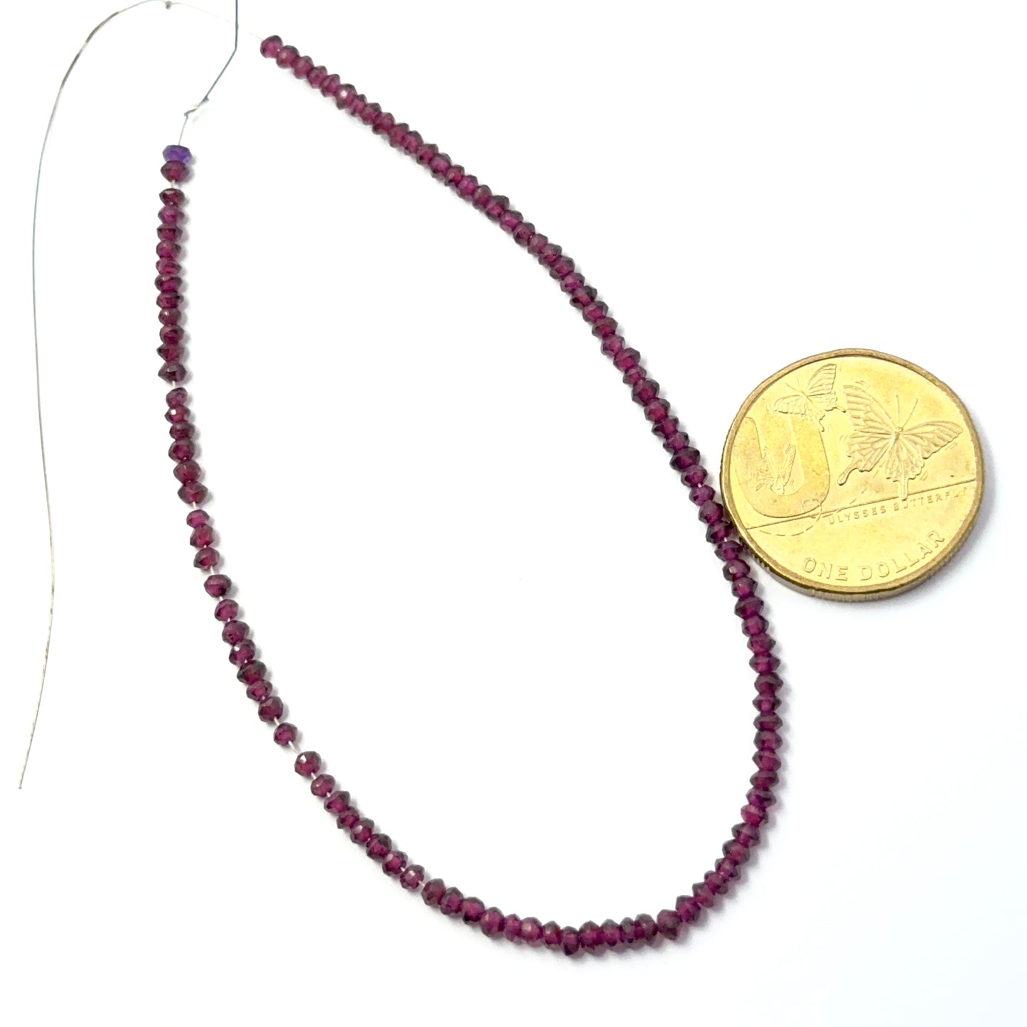 A coin placed near the garnet faceted rondelle 2.7–2.9mm gemstone for scale.