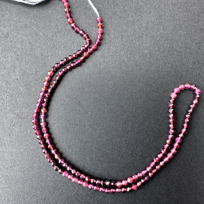 Close-up of garnet gemstone beads with glossy surface and uniform 2.4mm sizing for versatile jewellery making.