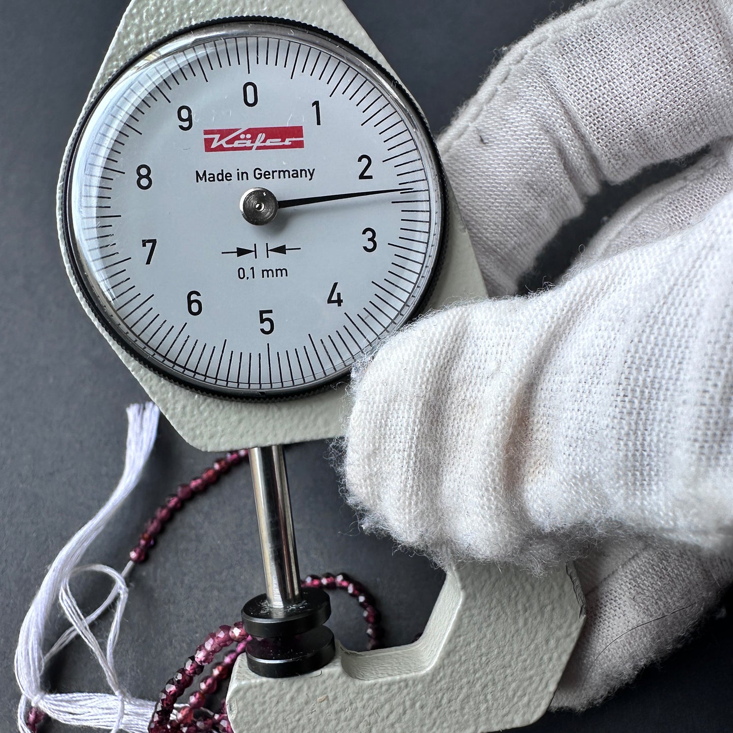A dial gauge measures the garnet faceted rondelle 2.4mm gemstone.