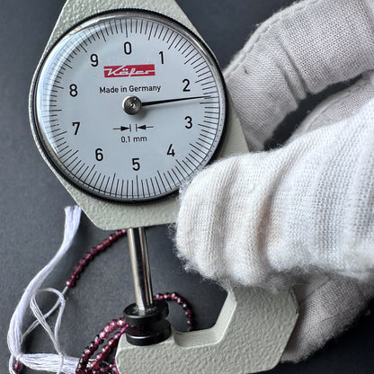 A dial gauge measures the garnet faceted rondelle 2.4mm gemstone.