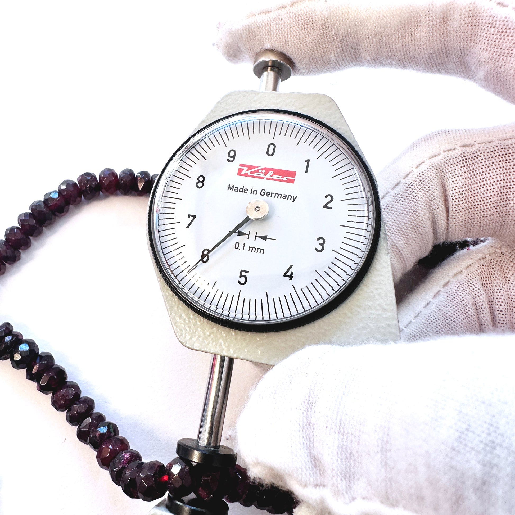 A dial gauge measures the Garnet faceted rondelle 6.0mm gemstone.