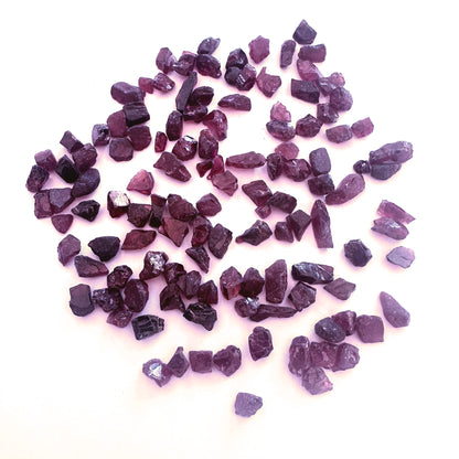 Undrilled garnet roughs arranged in a 20-piece set with earthy brilliance and varied shapes.