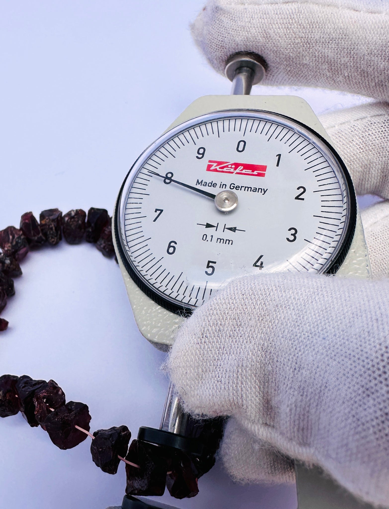 A dial gauge measures the Garnet rough 7–8mm gemstone.