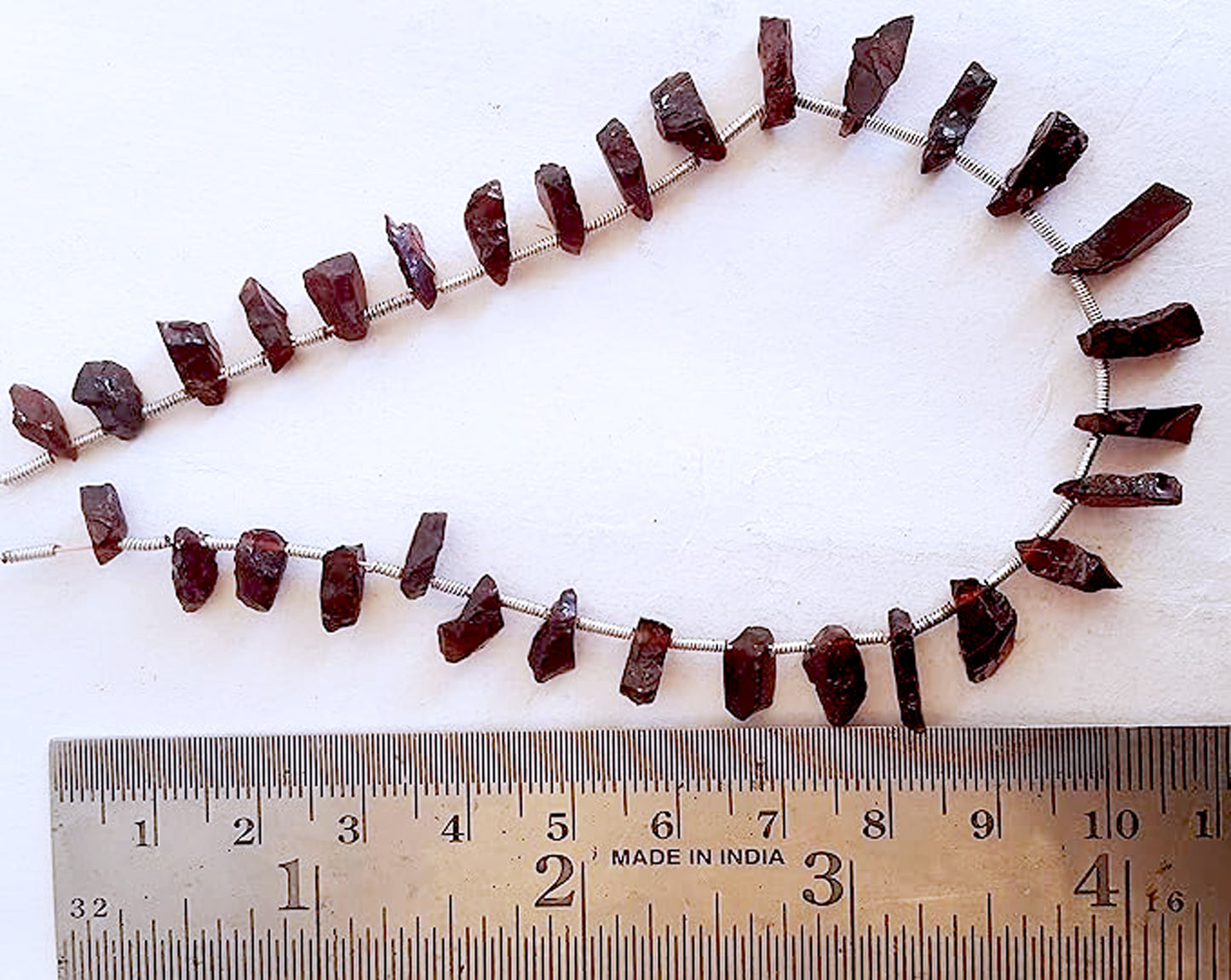 A ruler measures the garnet rough 7x4mm to 13x5mm gemstone, capturing its precise dimensions