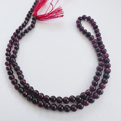 Close-up of Garnet smooth round beads with deep red tones and polished finish.