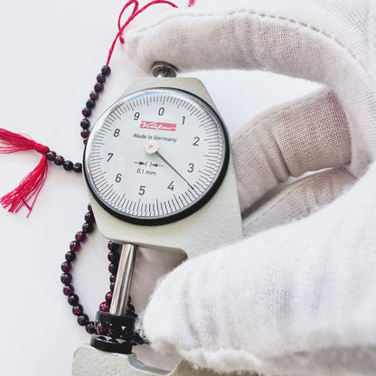 A dial gauge measures the Garnet smooth round 3.5mm gemstone.