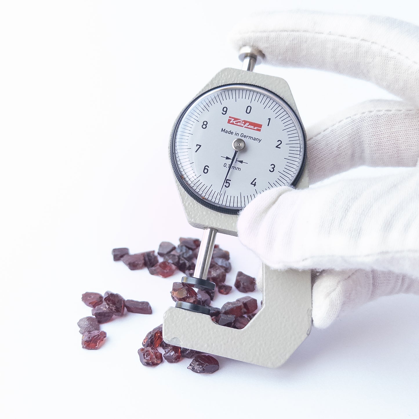 A dial gauge measures the Garnet rough 4–5mm gemstone.