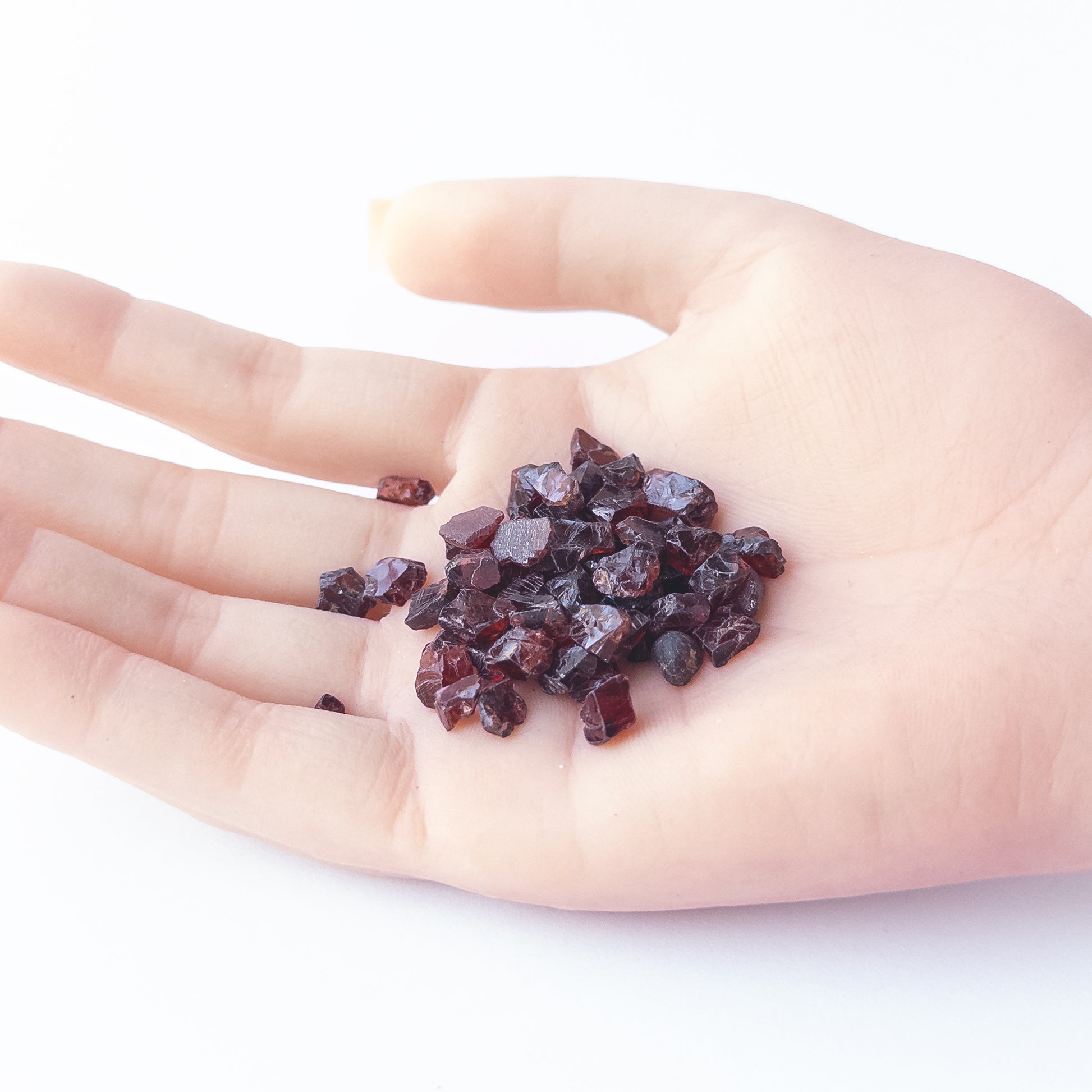 A person holds delicate pieces of Garnet rough, showcasing their natural design.