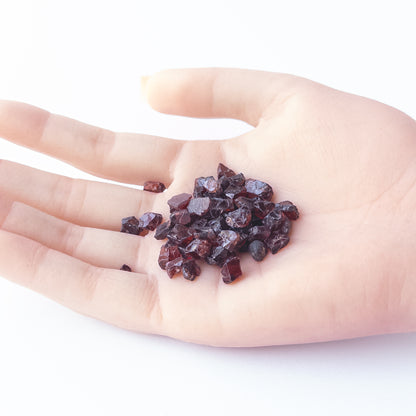 A person holds delicate pieces of Garnet rough, showcasing their natural design.