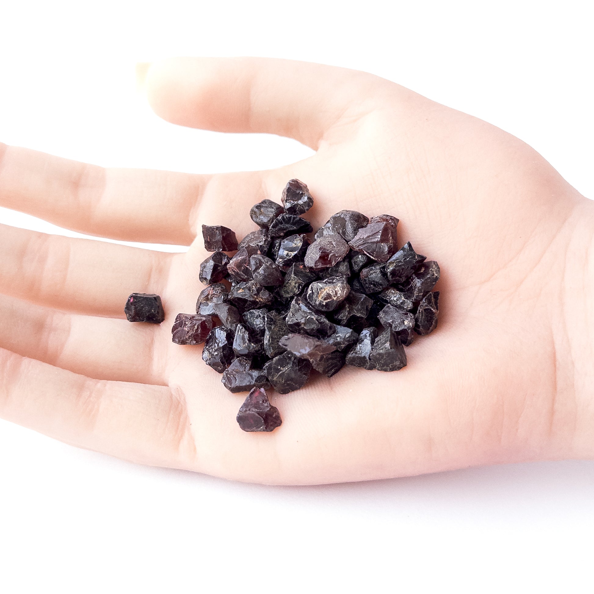 A person holds delicate pieces of Garnet rough, showcasing their natural design.