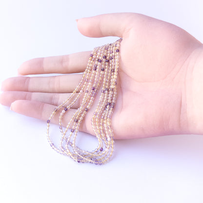 A person holds delicate strands of Golden Rutile beads, showcasing their faceted rondelle design.