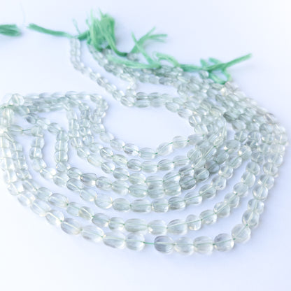 Close‑up of genuine Green Amethyst faceted oval beads showing their shine, clarity, and elegant 6–7mm cut.