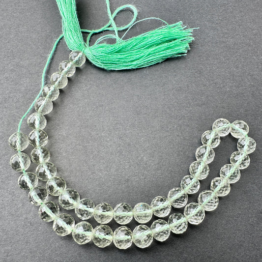 Green Amethyst faceted round beads with soft green tones arranged on a 23cm strand for jewellery making.