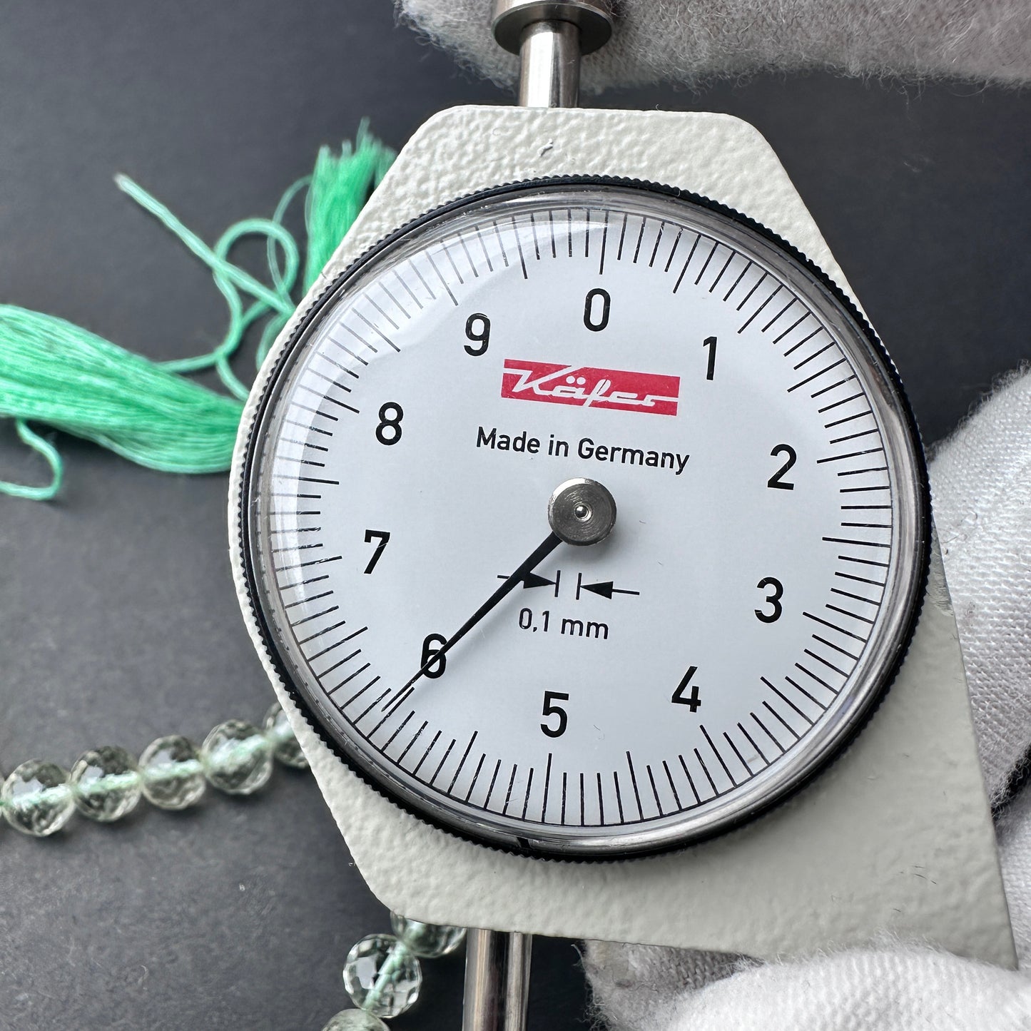 A dial gauge measures the Green Amethyst faceted round 6mm gemstone.
